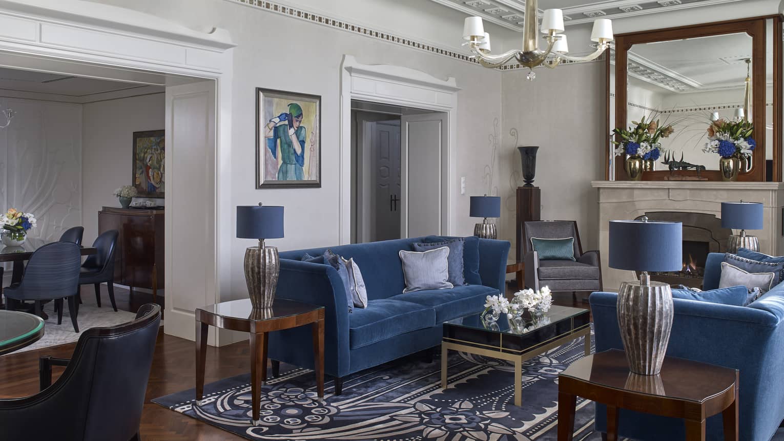 Living room with two blue velvet sofas, blue rug, crown molding and entryway into elegant dining room