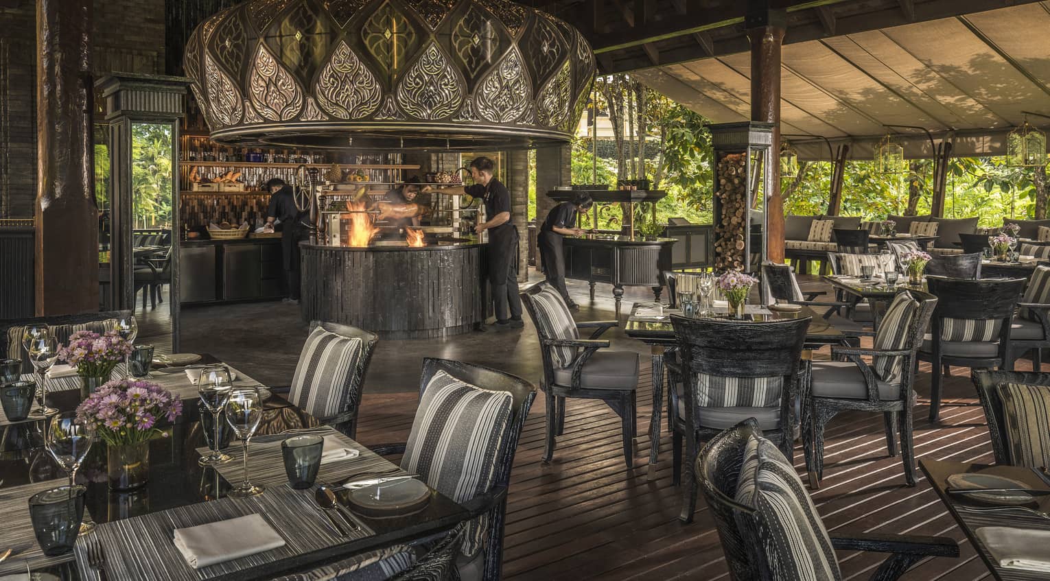 Restaurant with fire in open kitchen, dark wood floors and dining table/chairs
