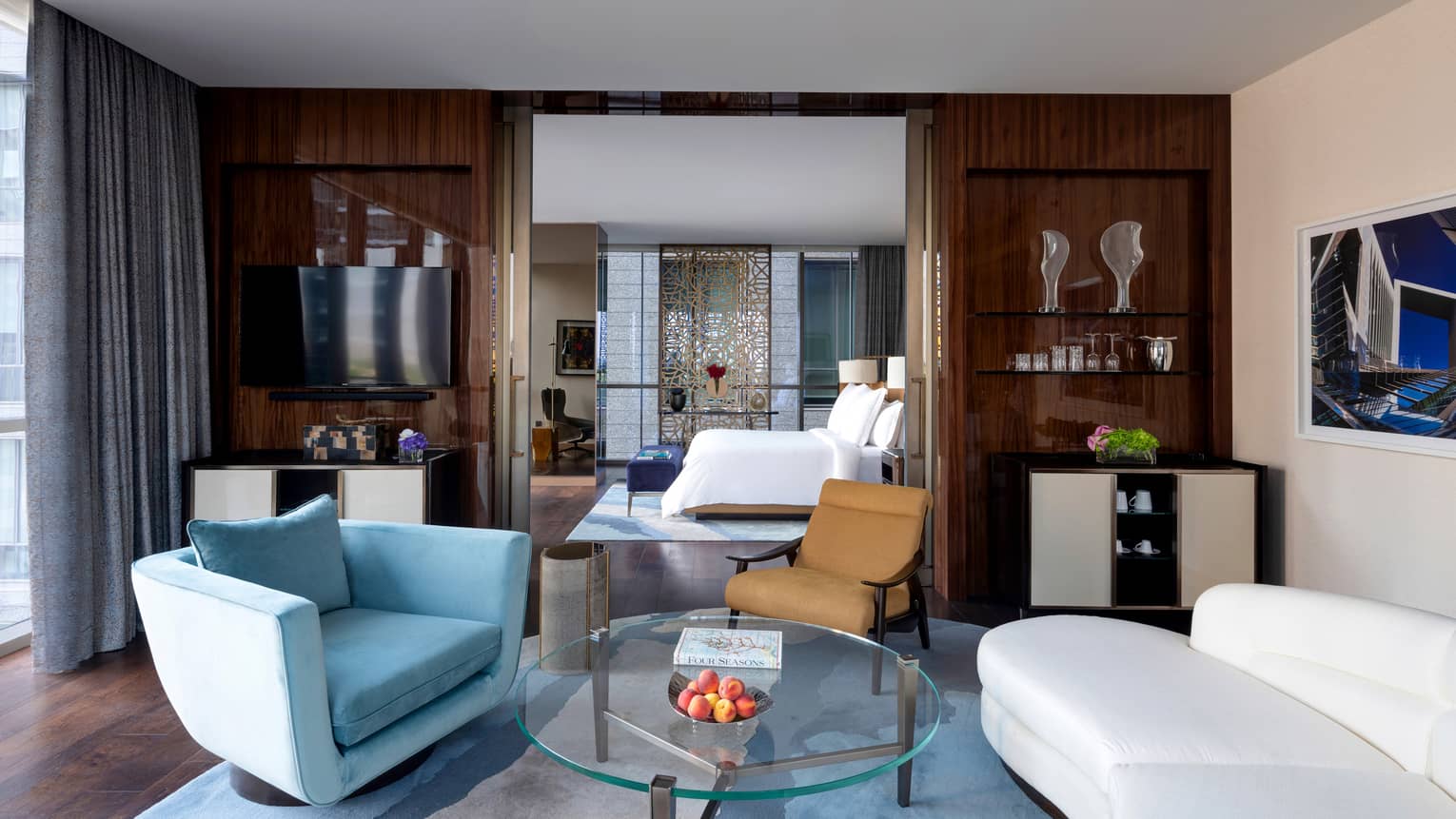 Living area with white curved sofa, light blue arm chair, glass table