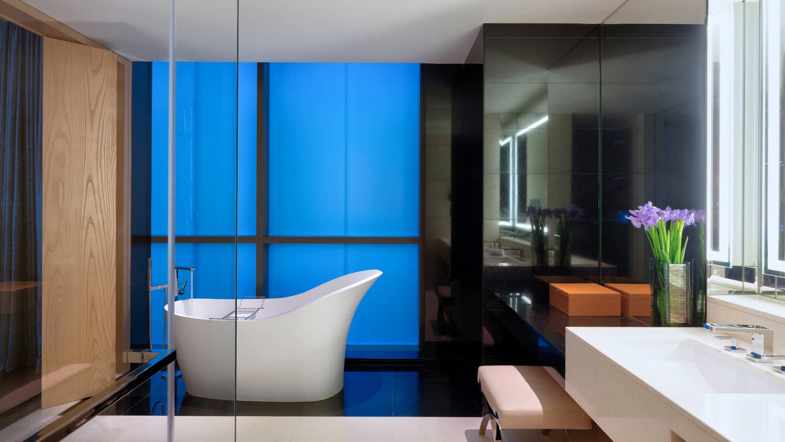 Bathroom with white freestanding tub, white vanity, glass shower