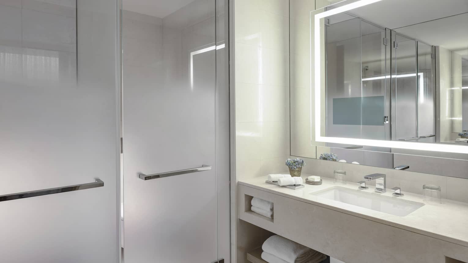 Bathroom with illuminated mirror, frosted glass walk-in shower