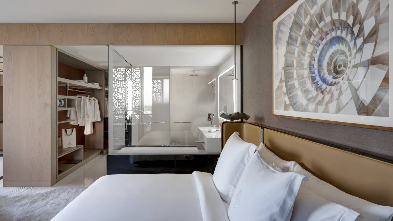 Bedroom with king bed, artwork hanging above, open bathroom