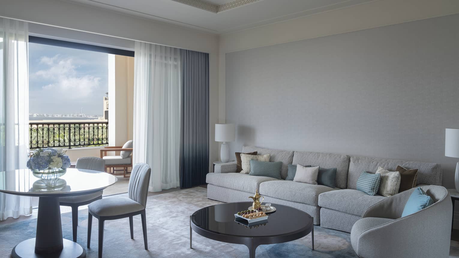 Hotel suite living room with sofa, arm chair, round table and two chairs, and a walk-out terrace