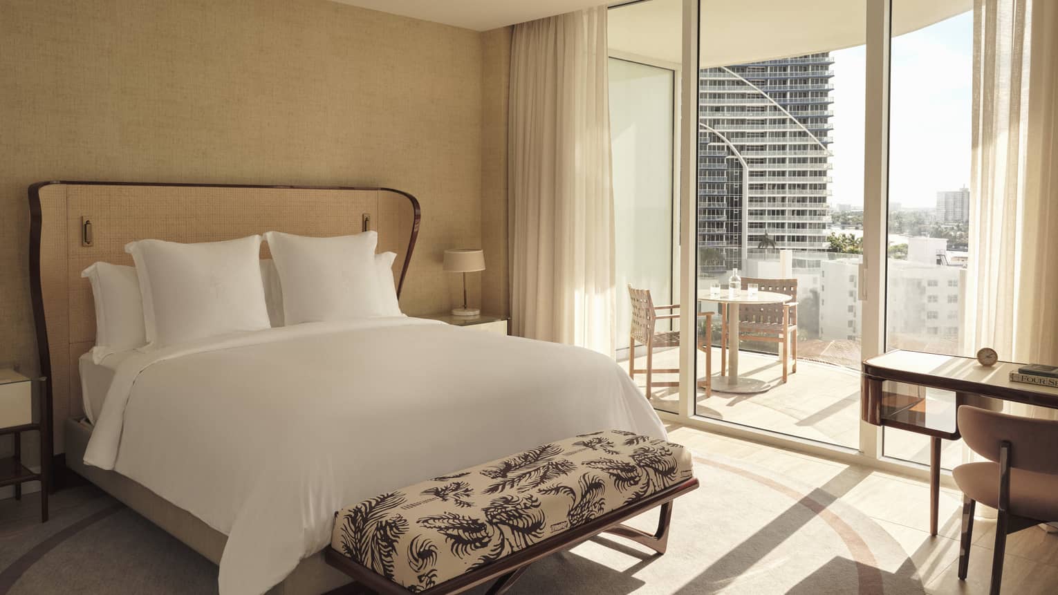 Hotel room with king bed, bench, glass doors to balcony