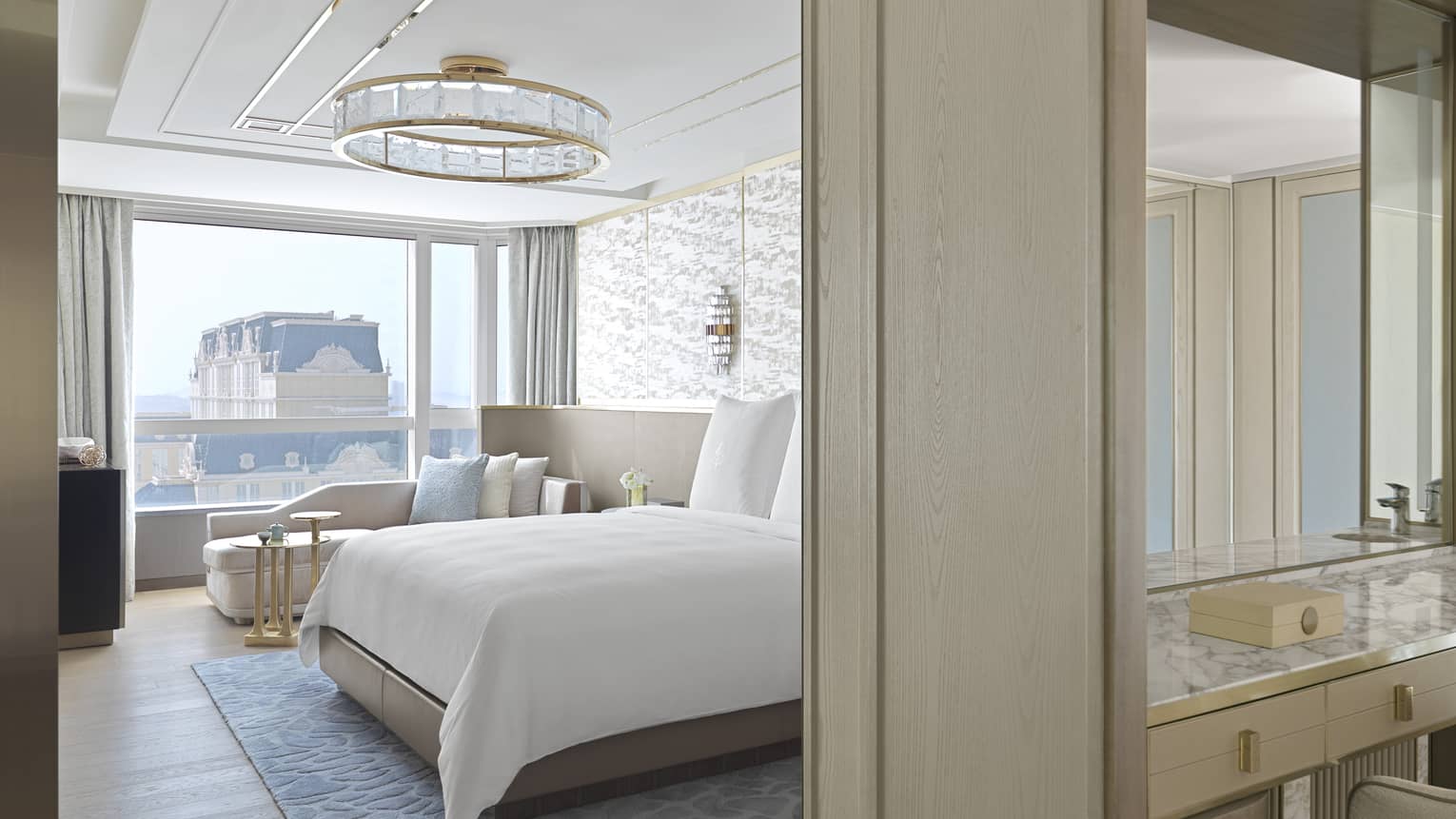 Elegant bedroom with bed, chaise, and separating wall with vanity at The Grand Suites at Four Seasons, Macao