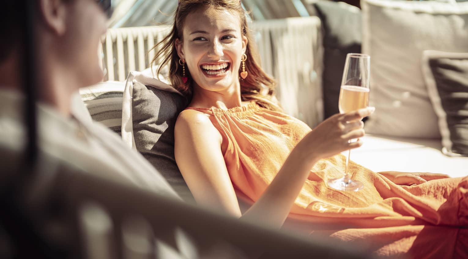 Smiling couple enjoys champagne on outdoor chaise lounge