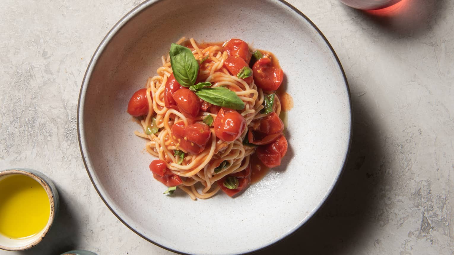 Spaghetti with tomatoes and basil on a white plate.