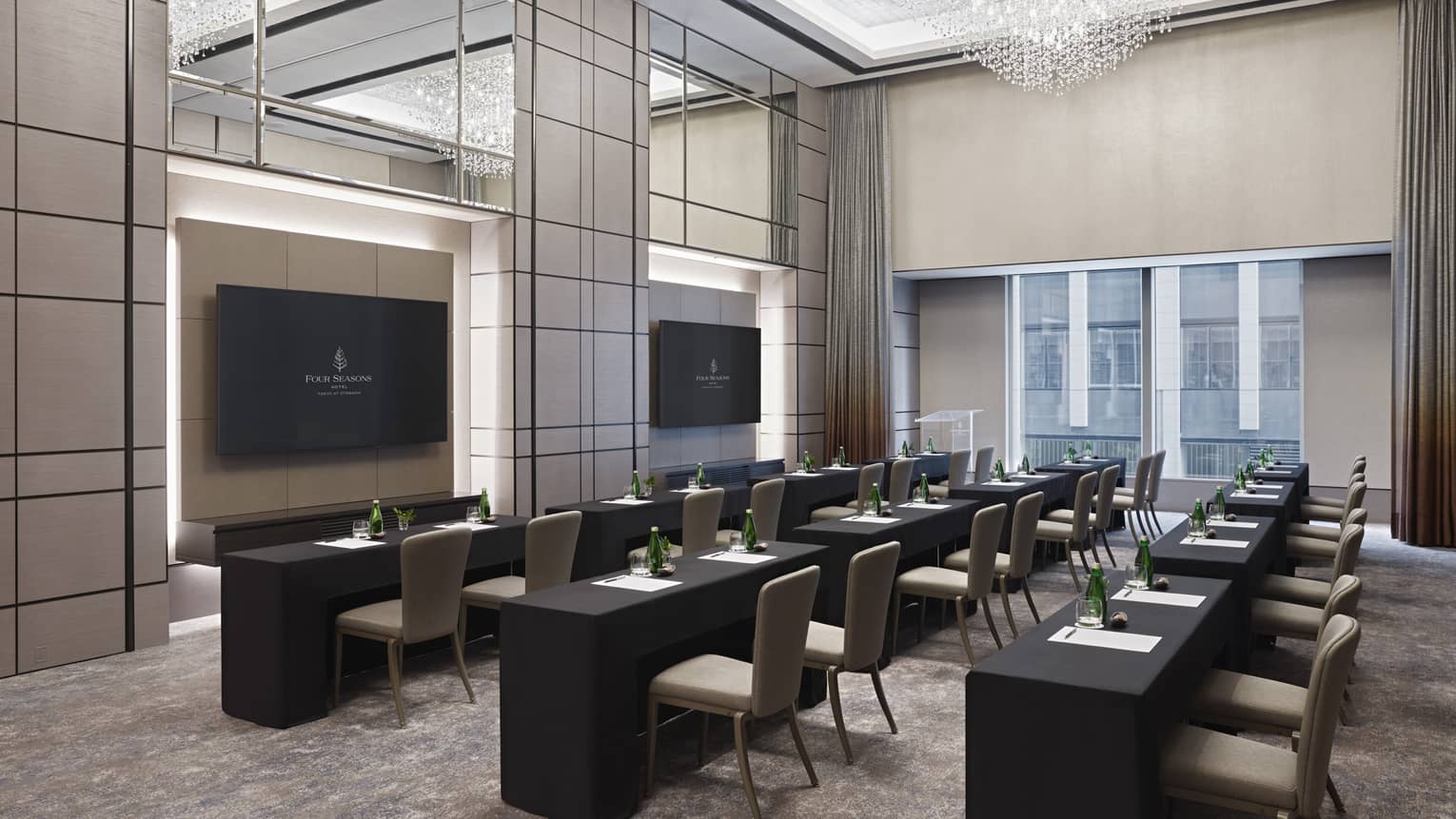 Meeting room set classroom-style with double chandeliers, black linens and two presentation screens 