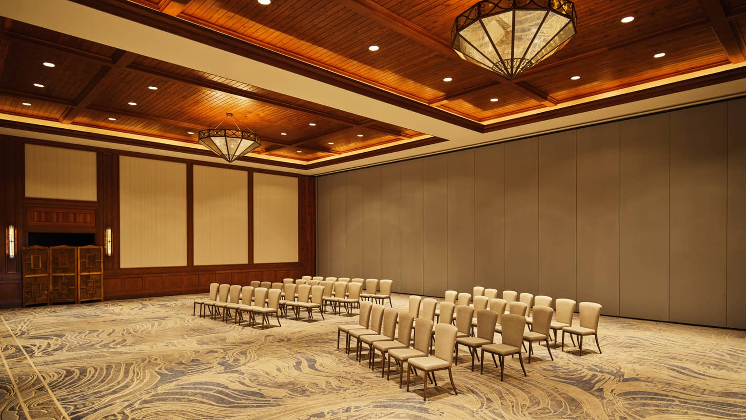 A room with a patterned carpet and chairs set up in rows