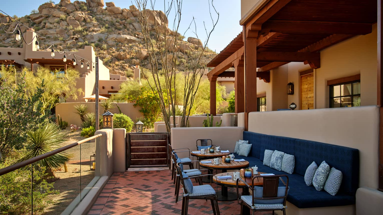 Outdoor terrace with booth seating and chairs and a view of the mountains.