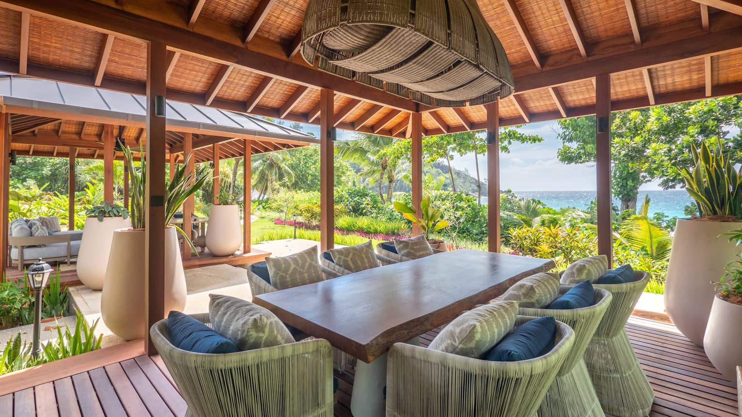 Dining table with eight chairs on covered wooden deck with beach view
