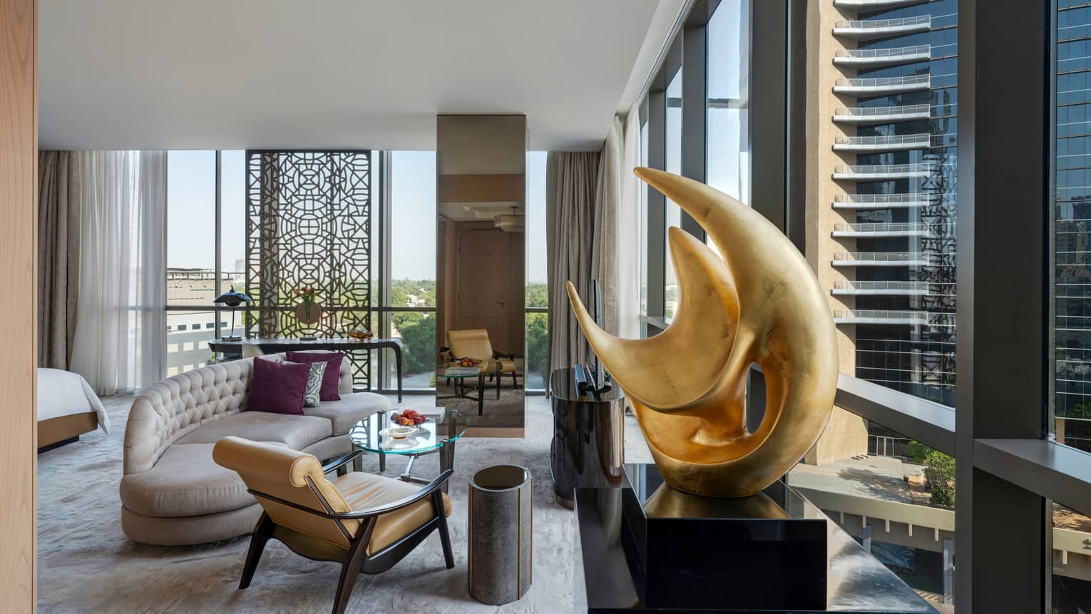 Living area with chaise, leather and wood arm chair, artwork, walls of windows