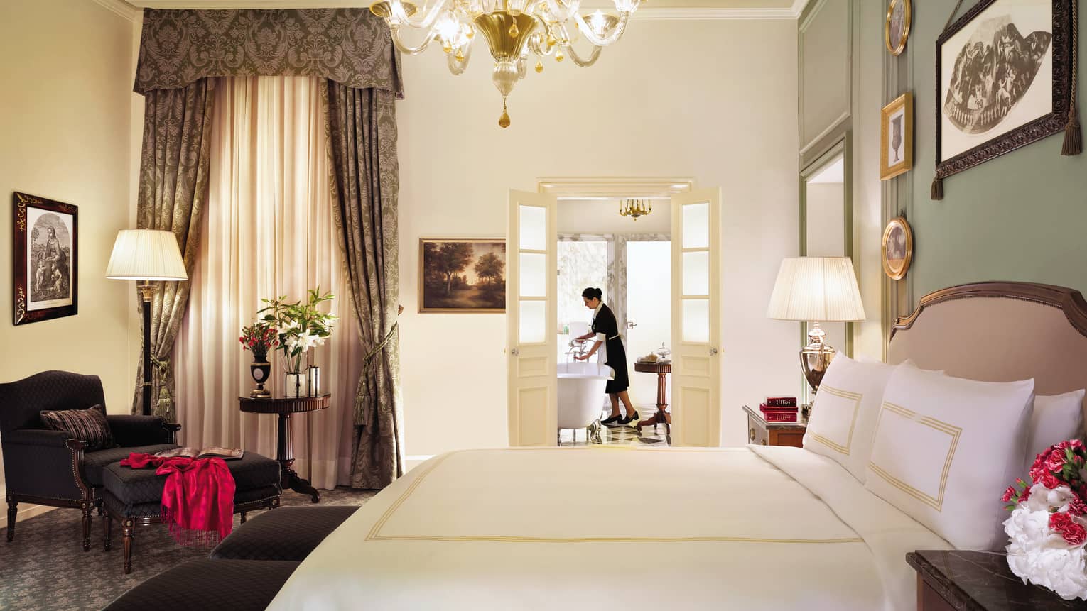 Hotel staff prepares bath in Four Seasons Junior Suite bathroom, beyond bed