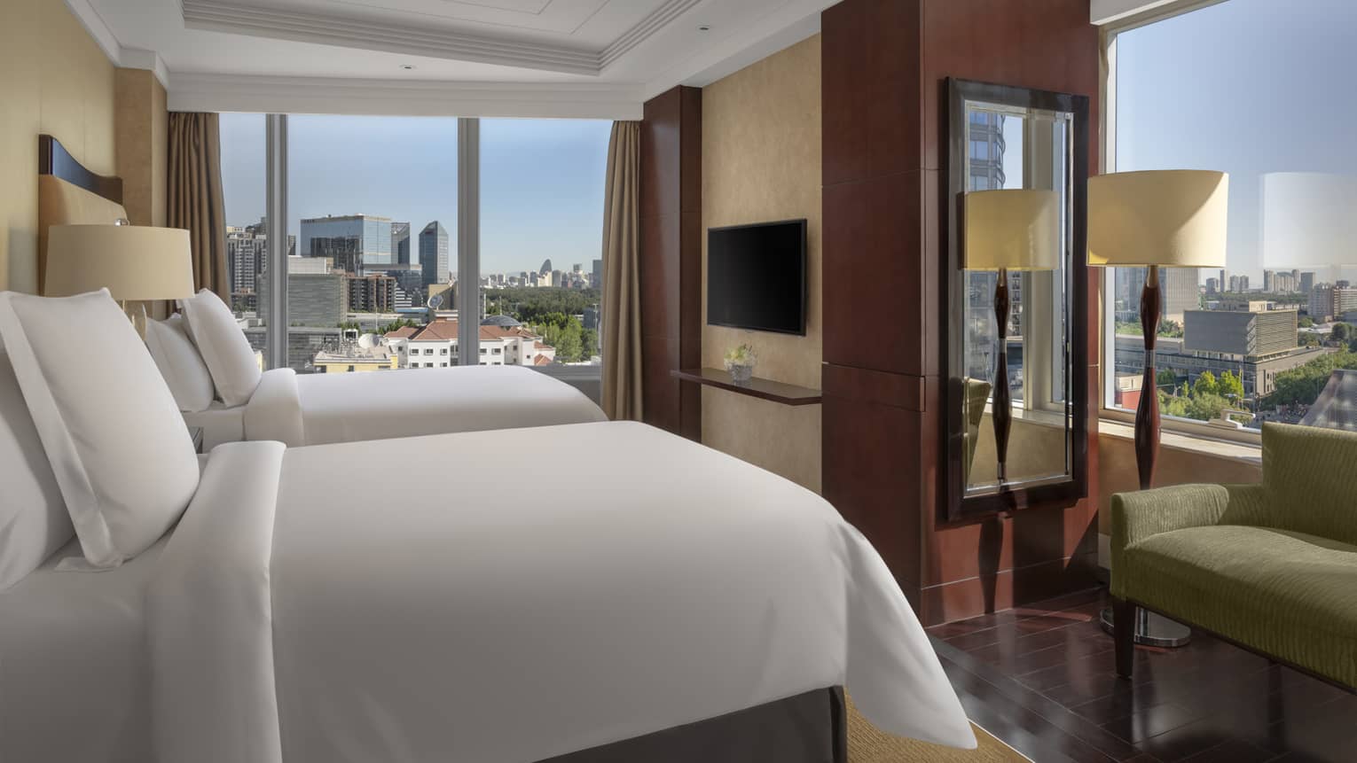 Hotel room with two single beds, windows on two walls, green love seat