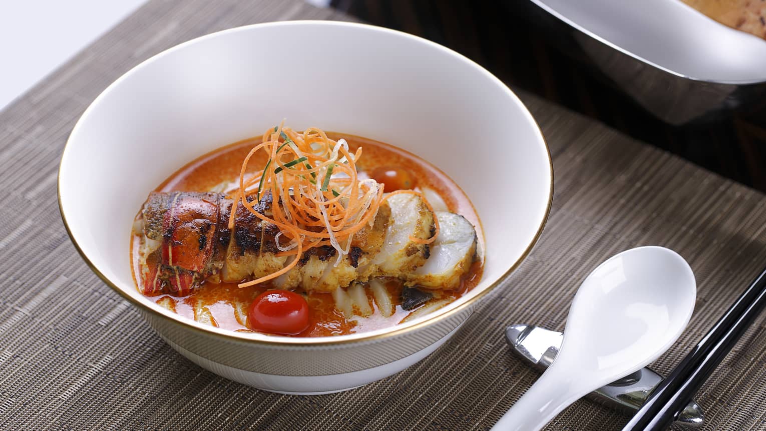 Bowl with lobster in red sauce, carrot garnish