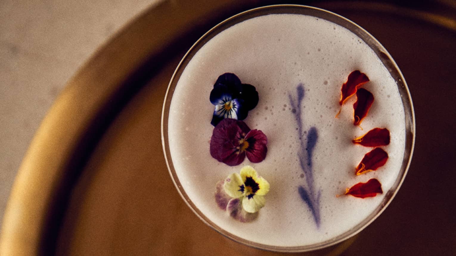 Two cocktails each garnished with dried florals and fruit