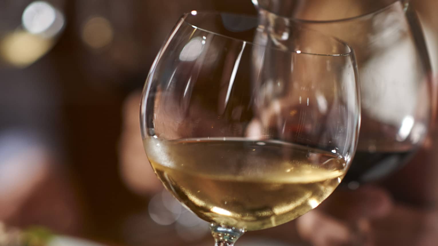 Two guests clink their wine glasses together at dinner