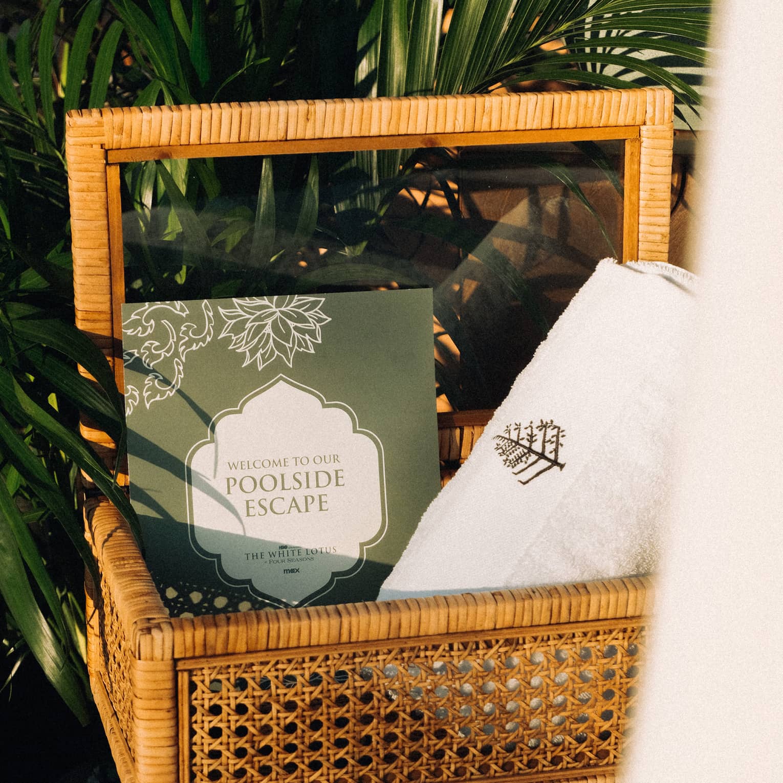 A basket beside a palm tree containing a Four Seasons towel
