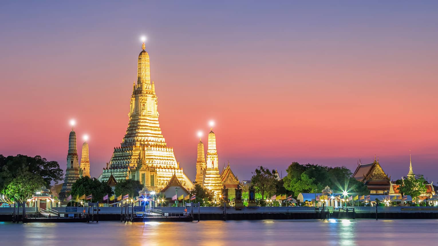A large structure covered in lights on the shore of water.