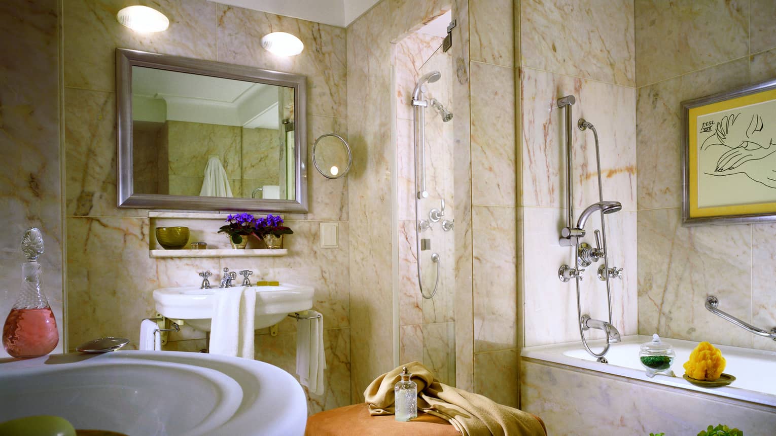 Sunny white-and-beige marble bathroom with large round sinks, bathtub and two showers
