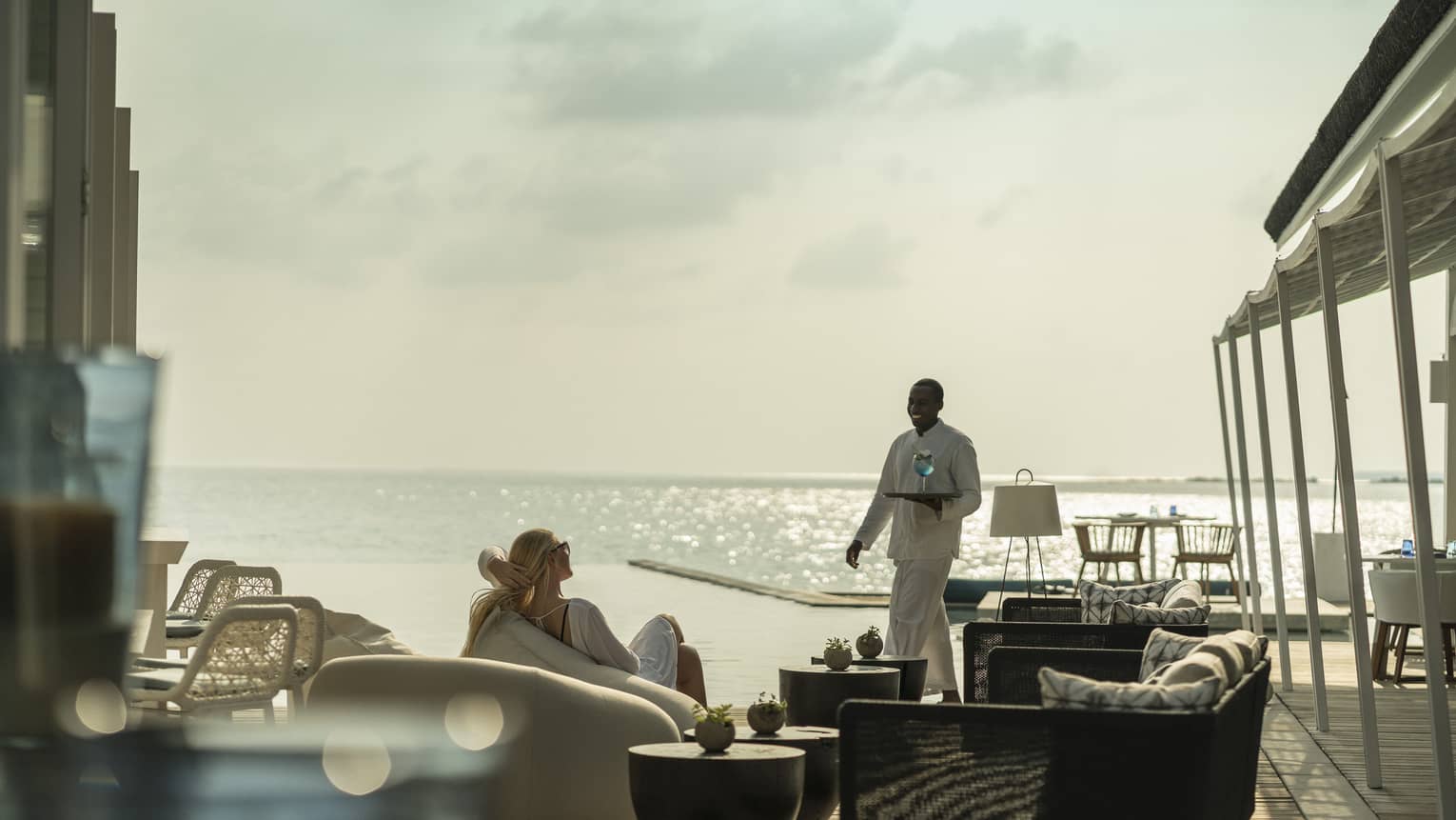 A guest receives a cocktail while relaxing outside at the Blu Beach Club