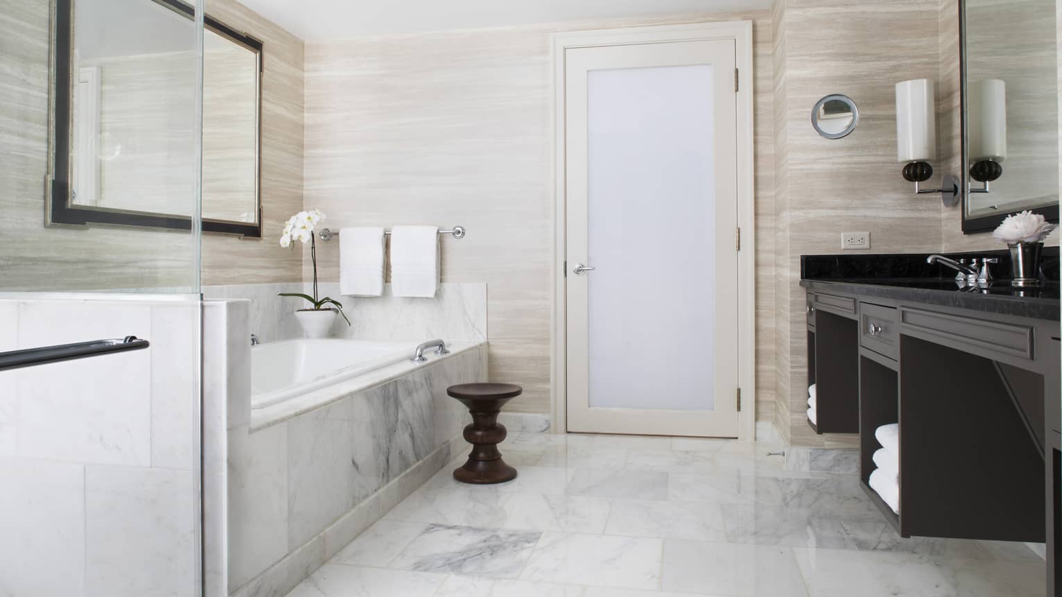 A light colored bathroom with a marble bathtub 