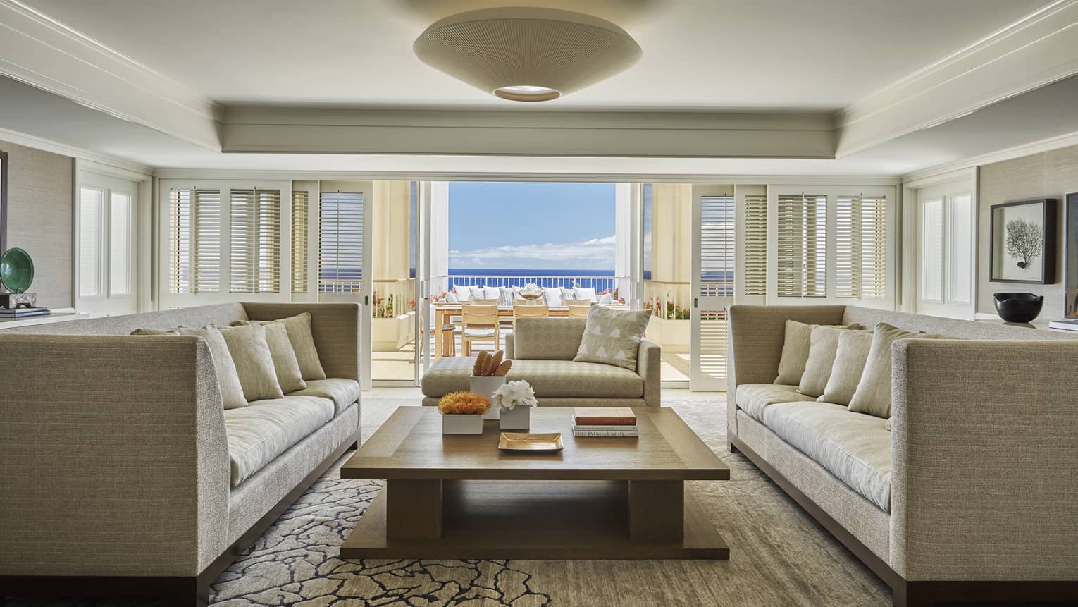 Living room with two matching sofas facing each other, large rectangular coffee table in the middle, sea view 