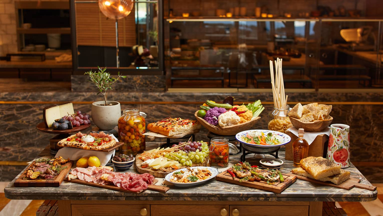 Sunday brunch spread, including jar of olives, charcuterie, breadsticks, focaccia, fruit and mezes