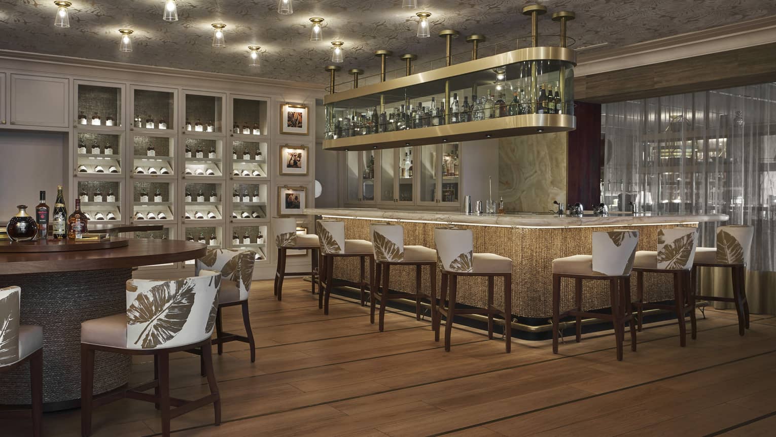 A dimly lit bar area with a large bar and white stools.