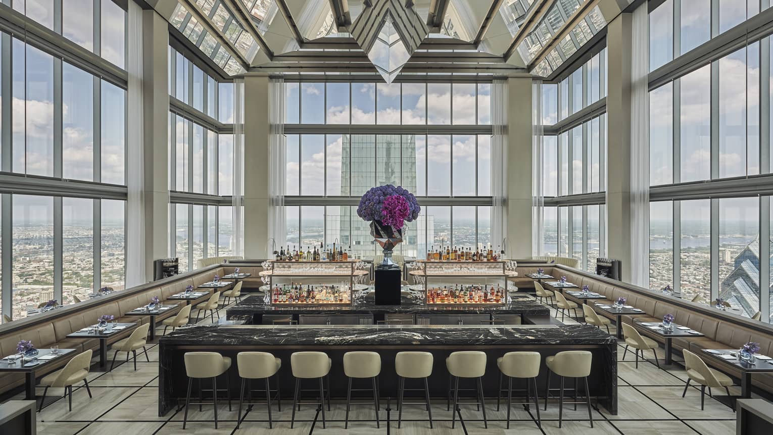 Glass penthouse bar and lounge with black and white marble bar, stools