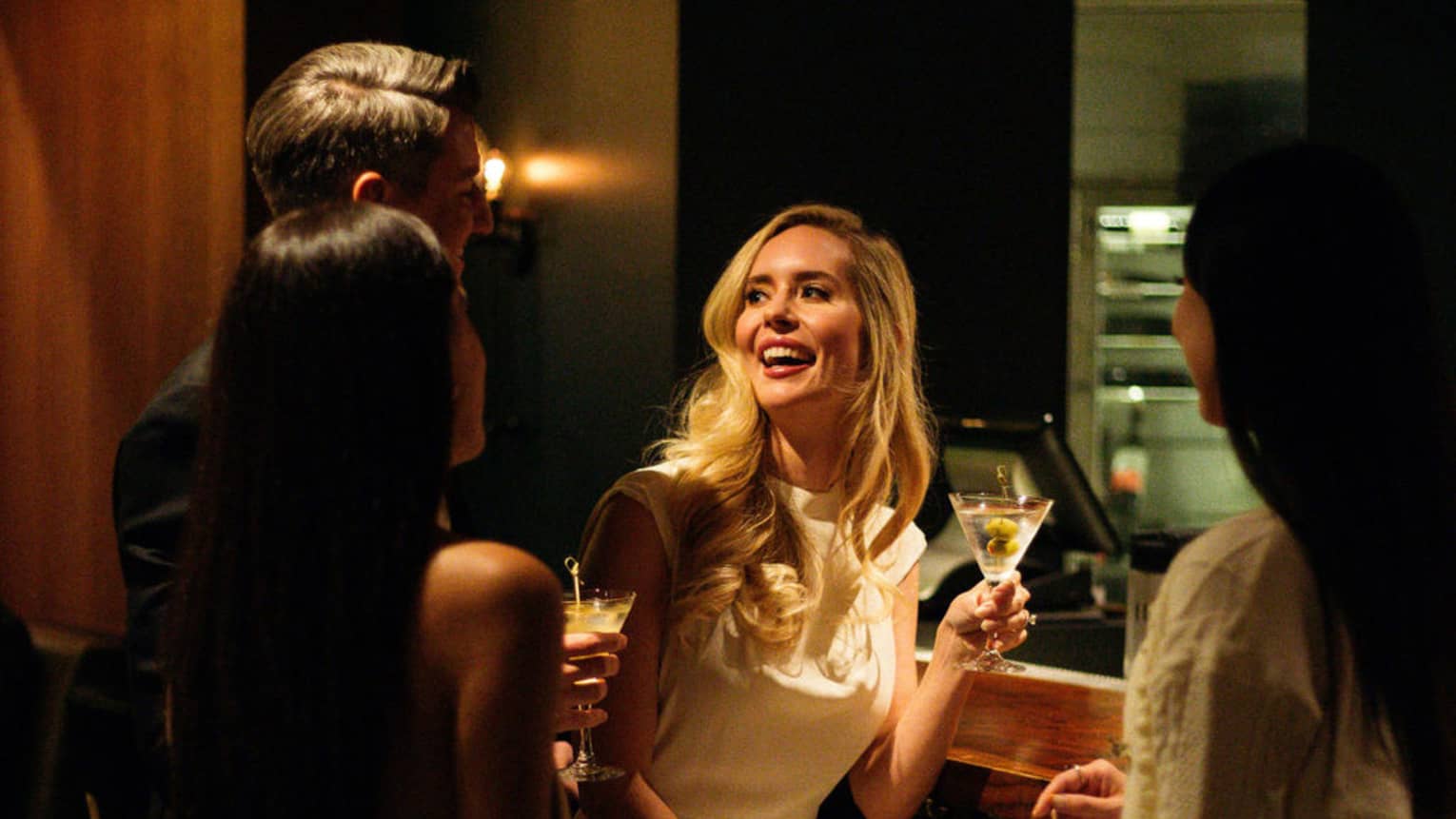 A group of people socializes in a bar setting.