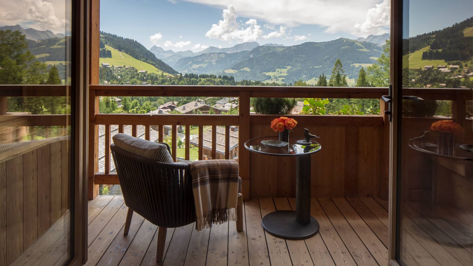Suites des Alpes patio chair with blanket, table with flowers on balcony overlooking French Alps