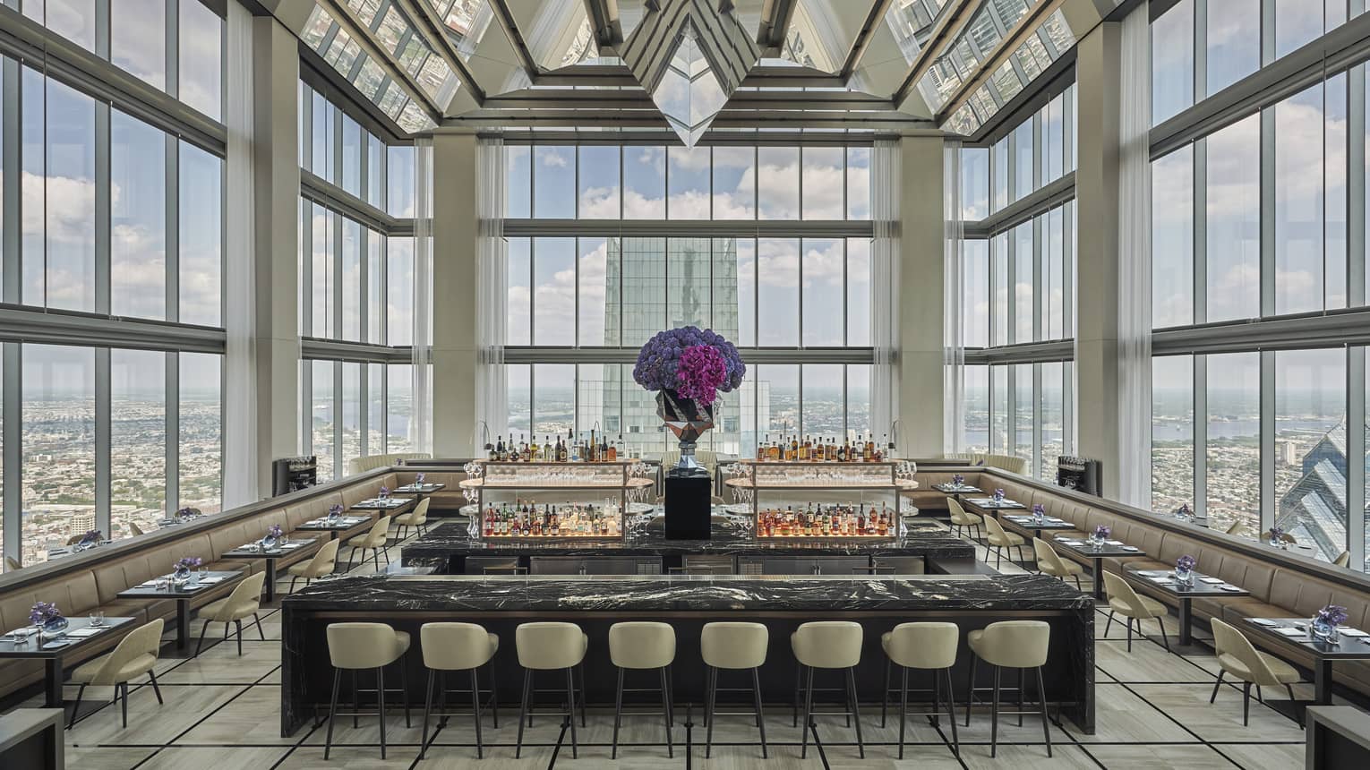 Glass penthouse bar and lounge with black and white marble bar, stools