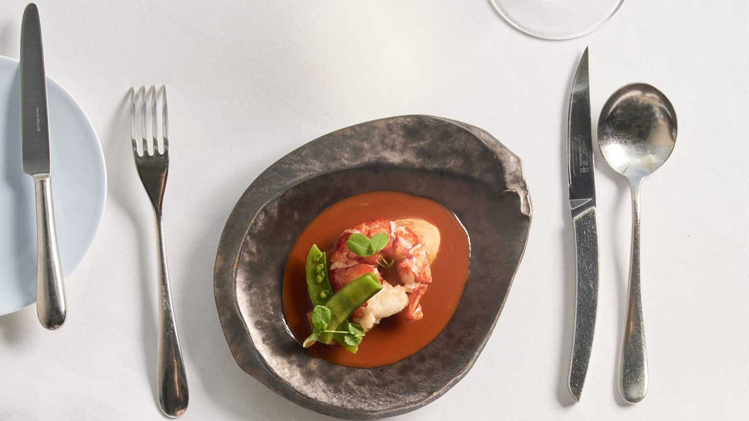 Table setting with a dark bowl of colourful food