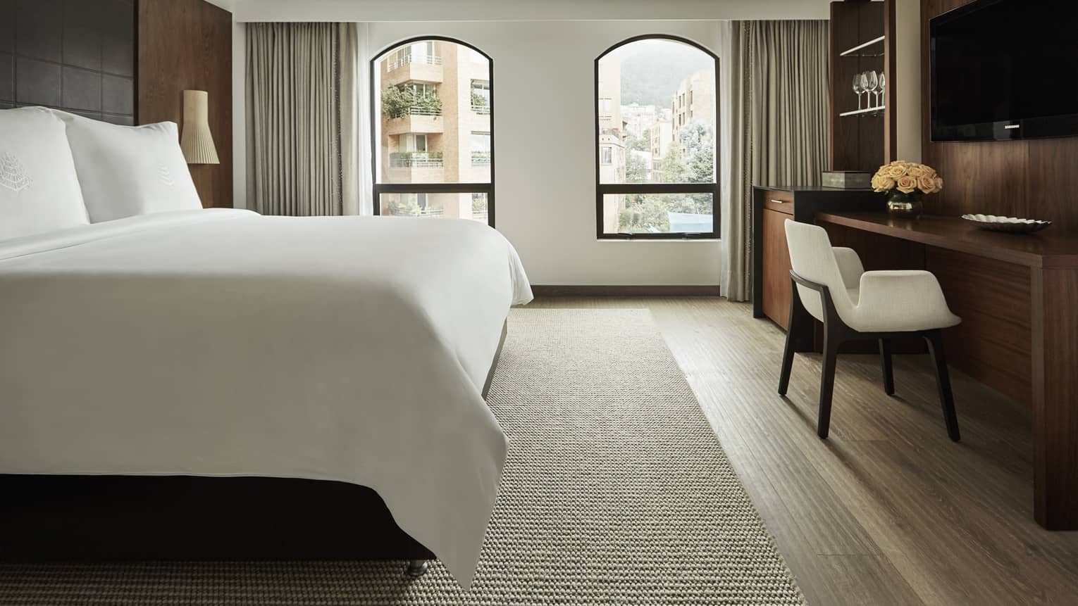 Superior Room bed, two windows with sunny city view, flat-screen TV over wood desk with white chair