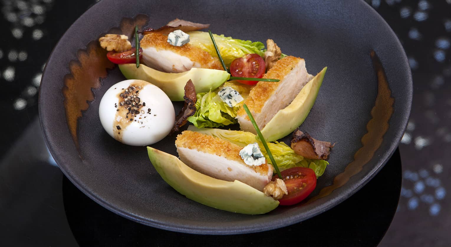 A Cobb Salad with chicken breast, a hardboiled egg, avocado, tomatoes, lettuce and blue cheese