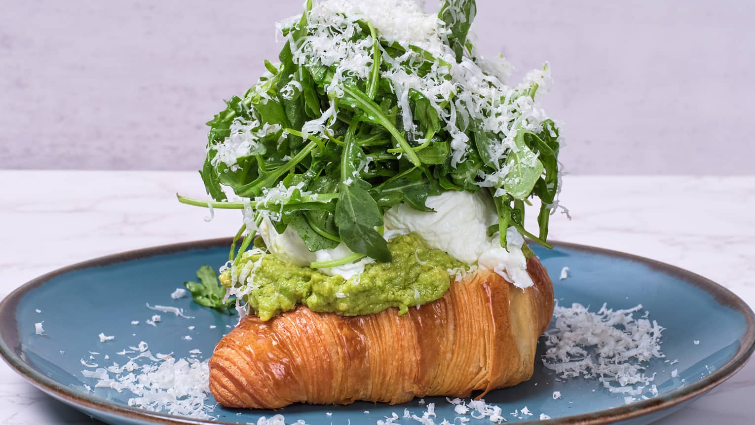 A croissant topped with avocado and lettuce