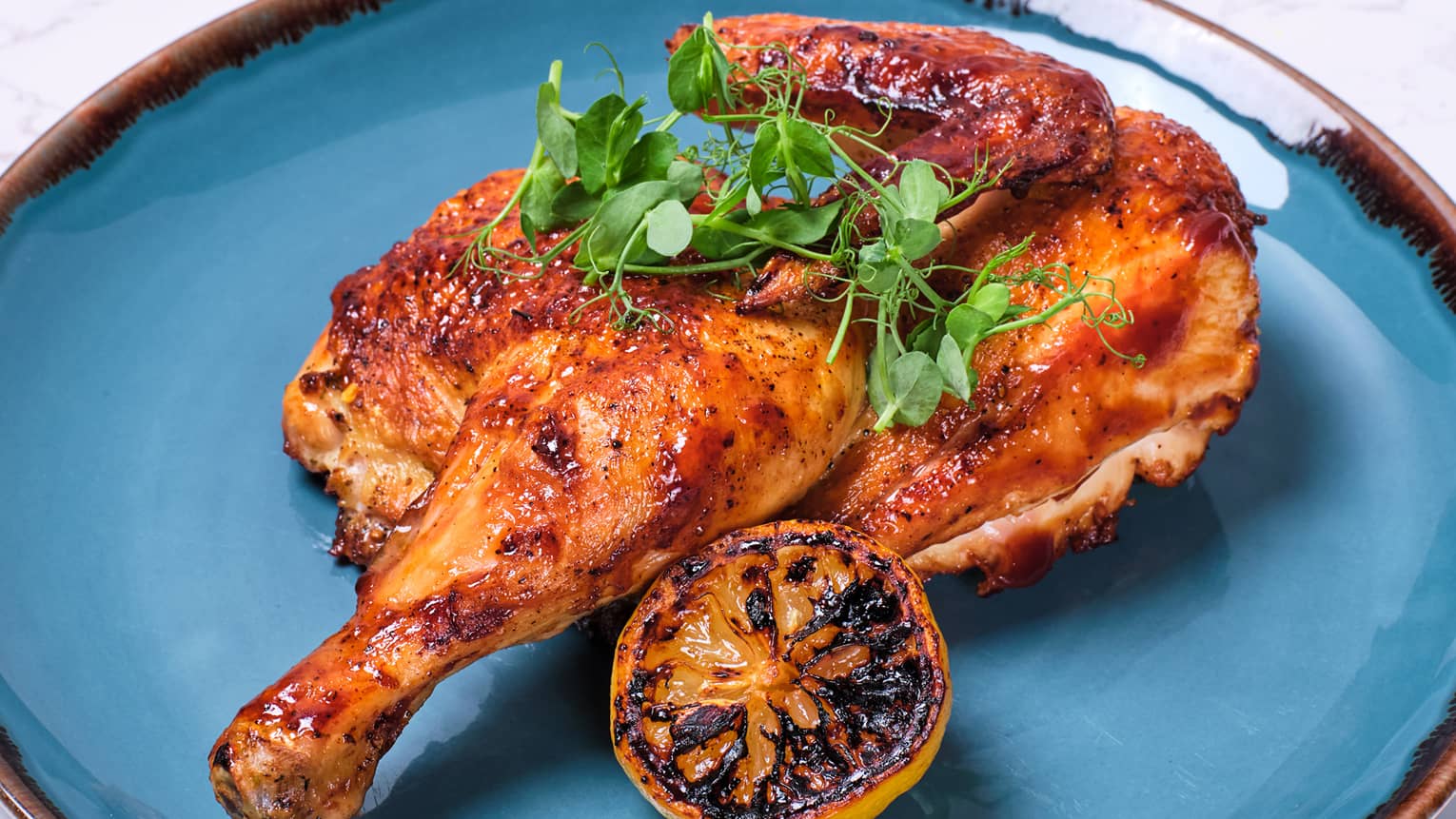Half chicken on a plate with a lemon slice