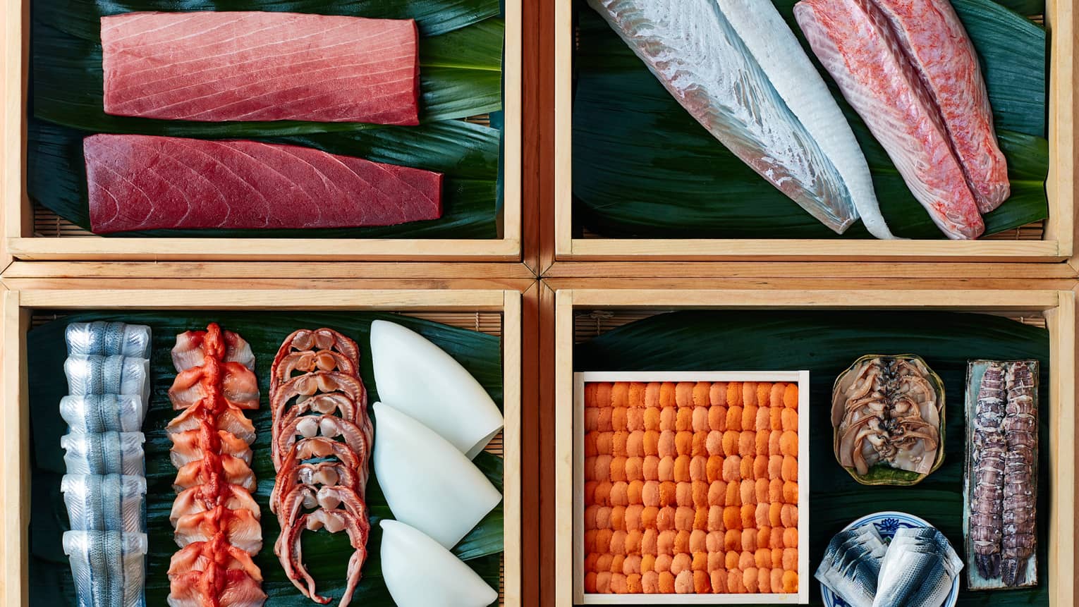 Four bamboo boxes with raw fish filets, sashimi sushi sliced fish