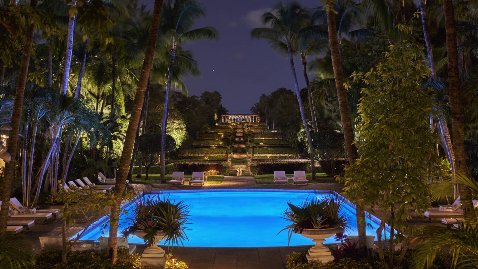 An outdoor pool lit up with lights at night.