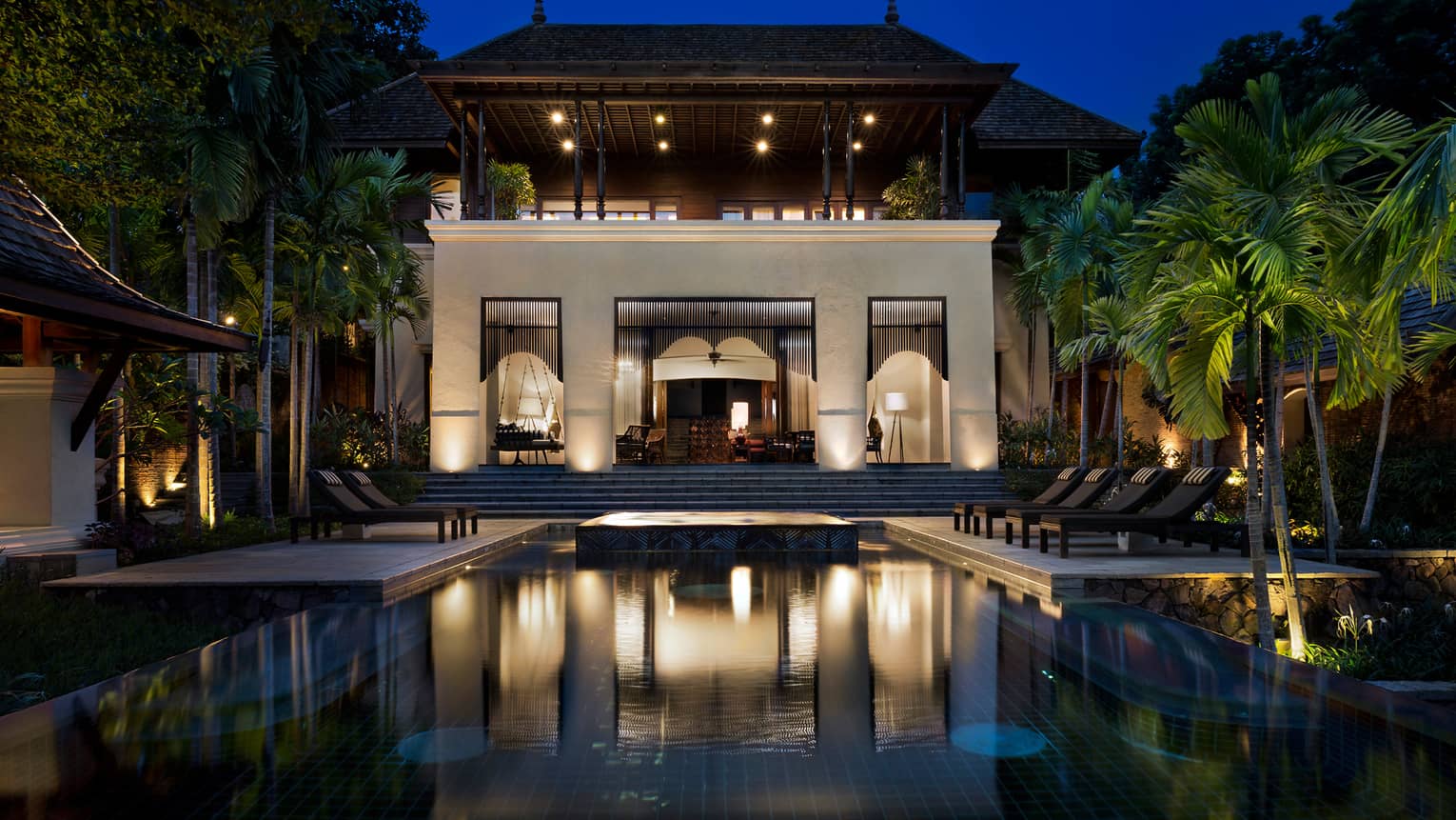 Large Four-Bedroom Residence Villa at night with lights, outdoor pool and palms 