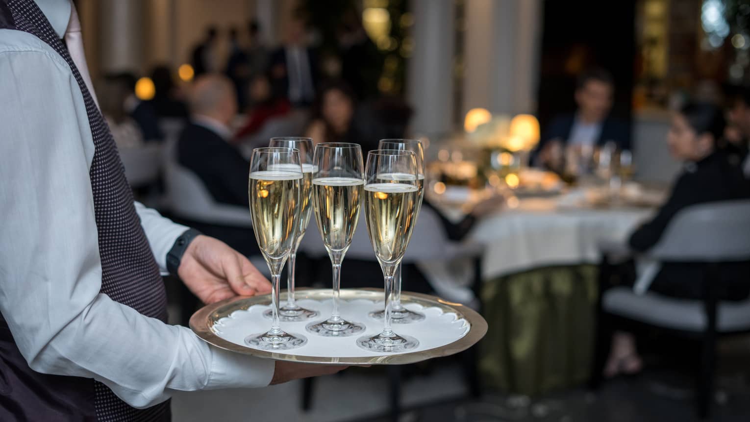 A team member carrying a tray of champagne.