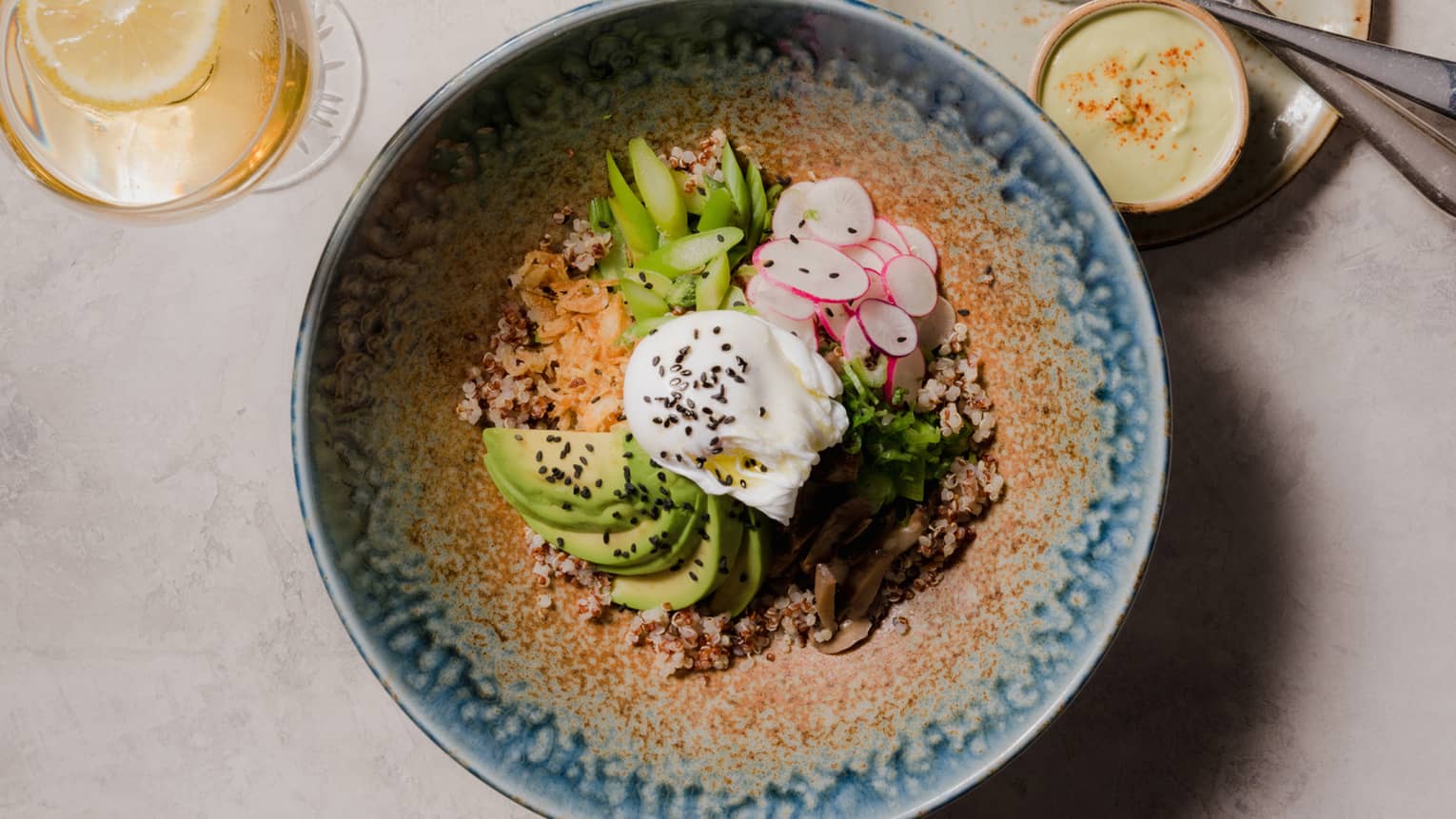 Korean grain bowl with avocado, radishes and fried egg in a patterned blue dish