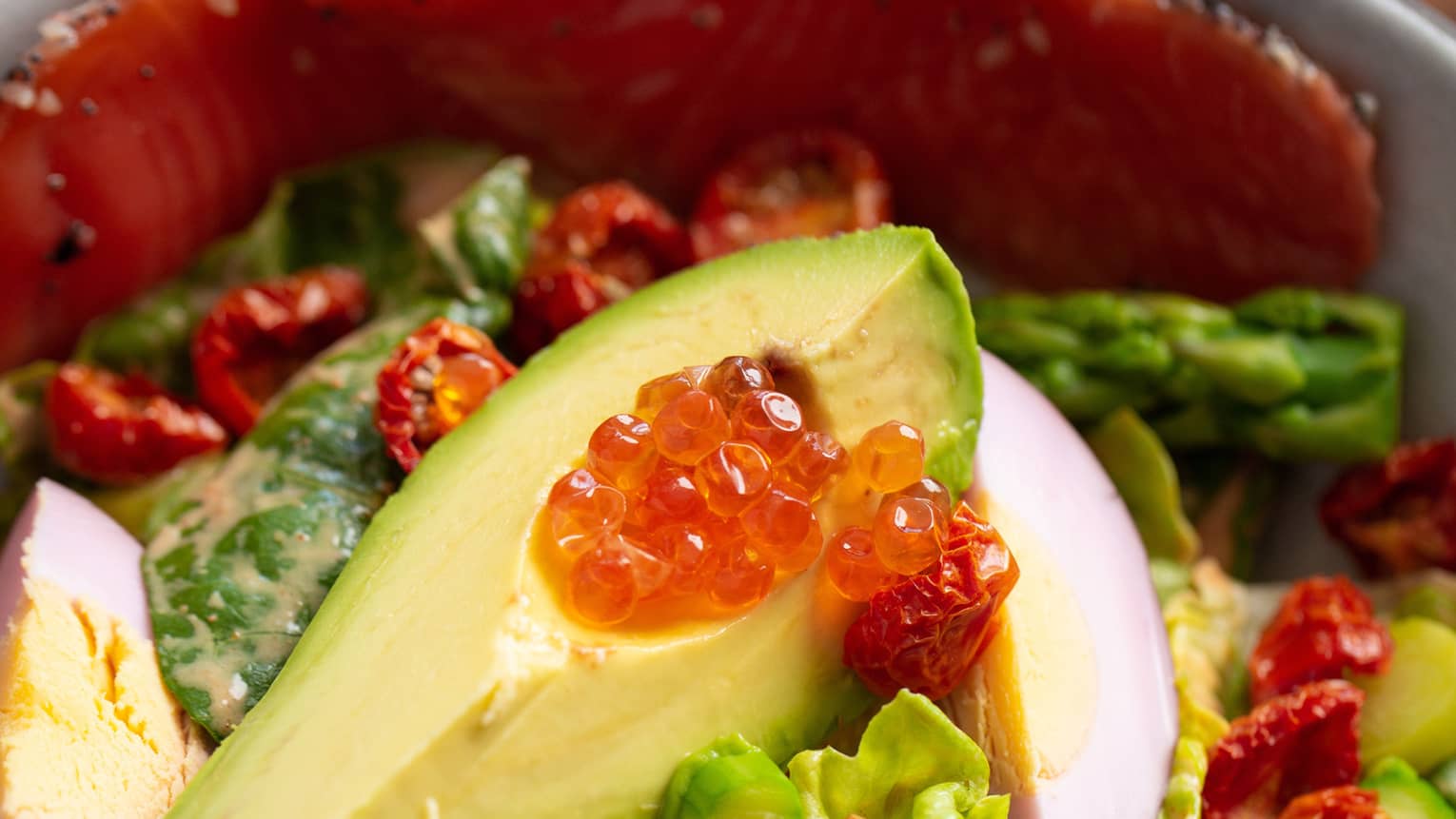 Fish, avocado and greens in a bowl.