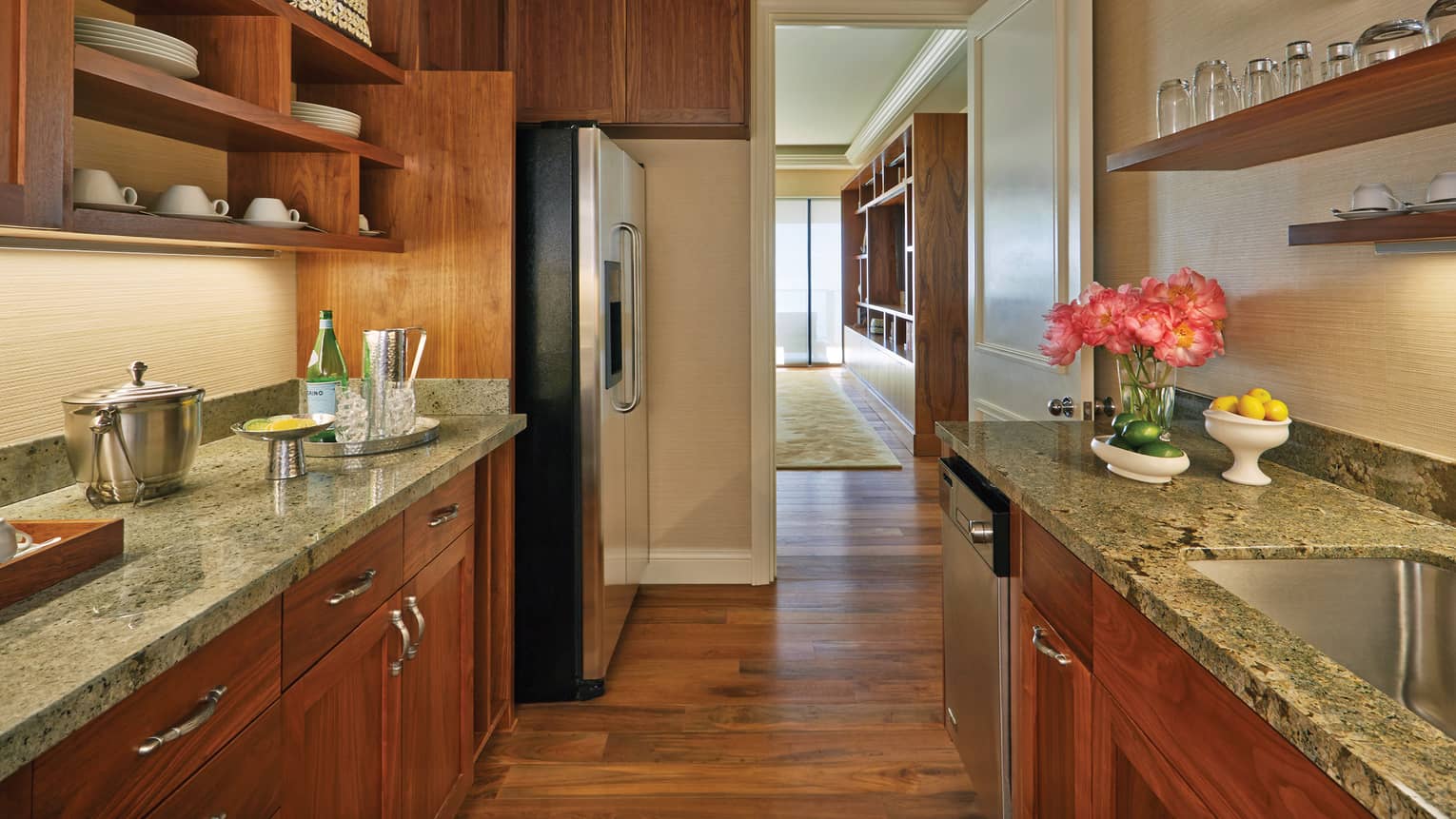 Modern kitchen with granite countertops, stainless steel appliances, flowers and wooden cabinetry in a luxury resort suite