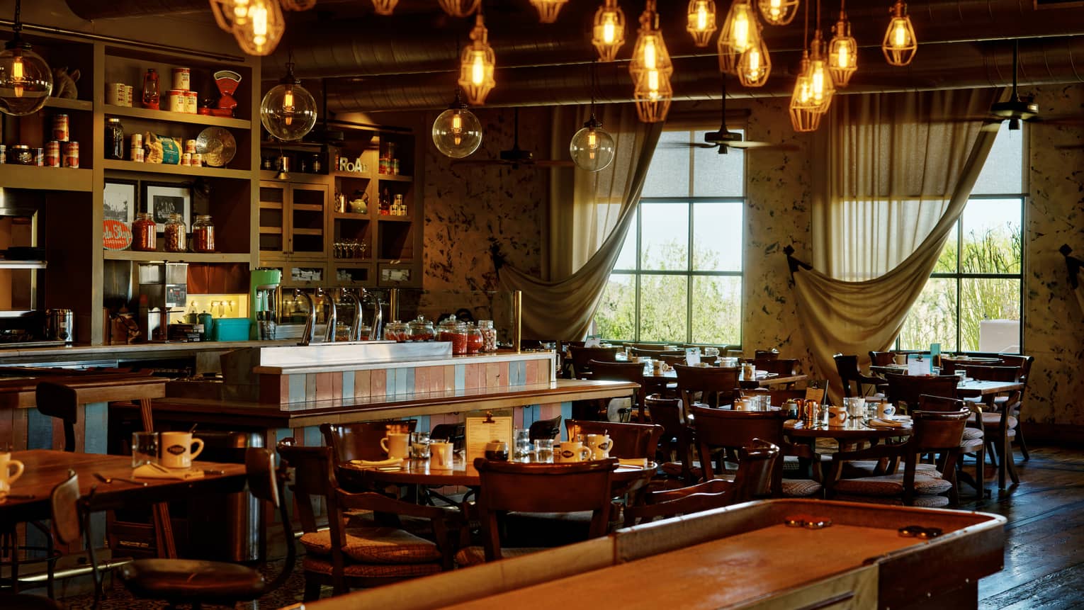 Proof restaurant with shuffleboard table and hanging lights, at Four Seasons Resort Scottsdale