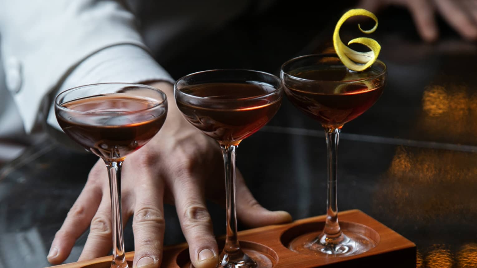 Row of three cocktails ? Classic Manhattan, De La Louisiane and Vieux Carr� ? in wooden stand