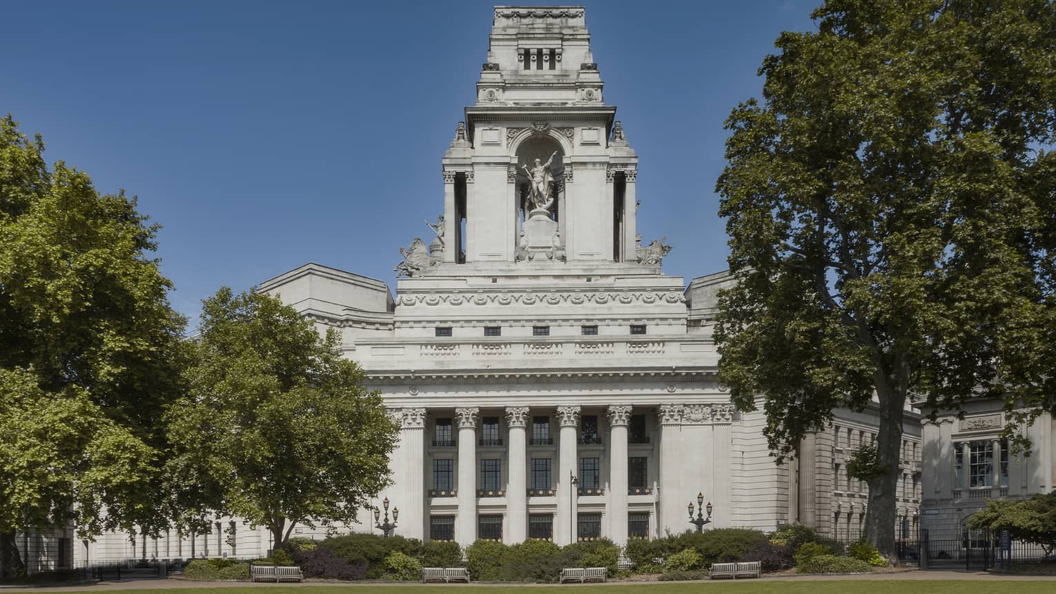 Exterior of Ten Trinity Square Hotel flanked by trees and blue sky in backdrop