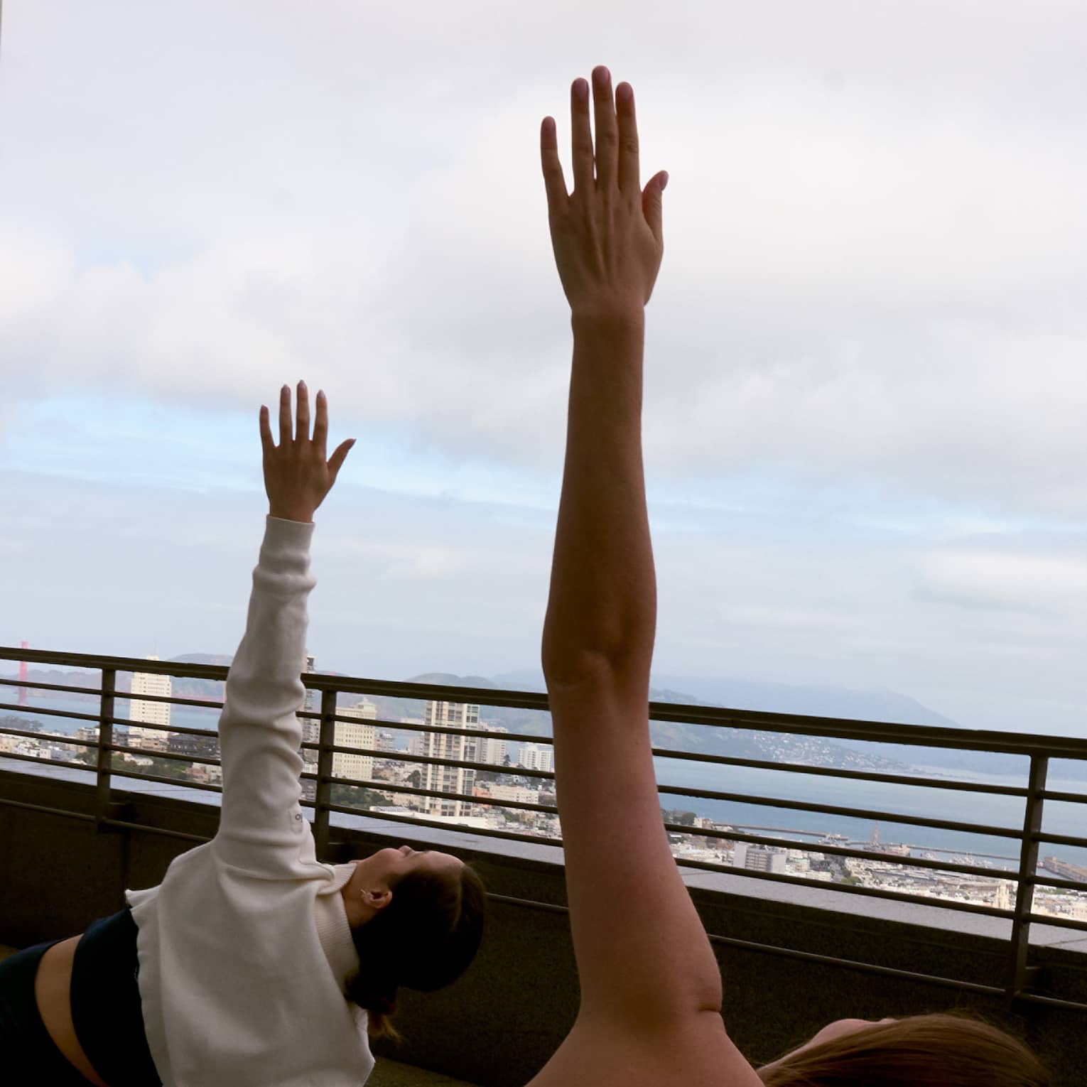 Two guests doing yoga on a rooftop with the sky in the background