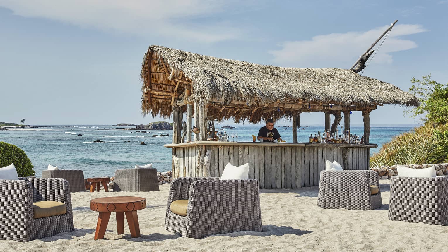 A man works at shack bar on the beach, with the water in the background